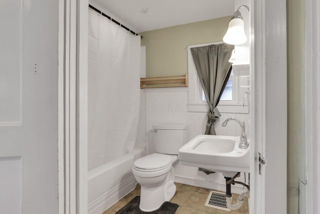 bathroom featuring toilet and shower / bath combination with curtain