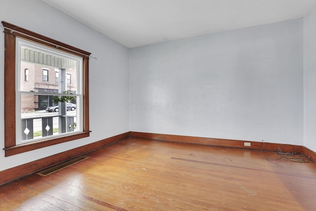 spare room featuring light wood-type flooring, plenty of natural light, and baseboards