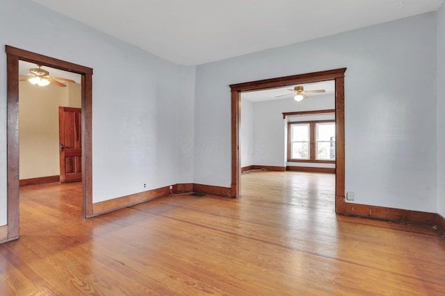 unfurnished room with light wood-style flooring, a ceiling fan, and baseboards