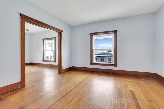 unfurnished room featuring light wood-style flooring, healthy amount of natural light, and baseboards