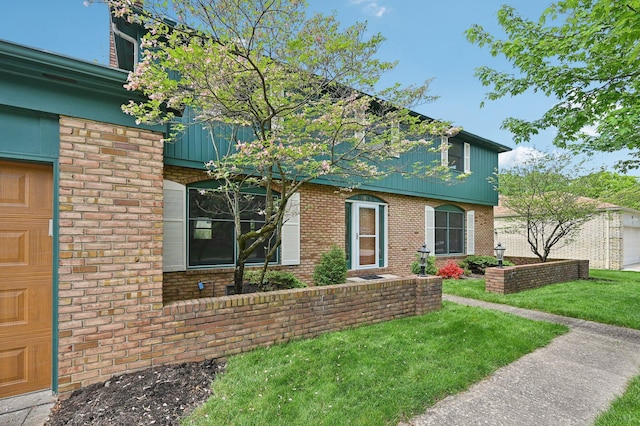 view of front of house with brick siding, a front yard, and a garage