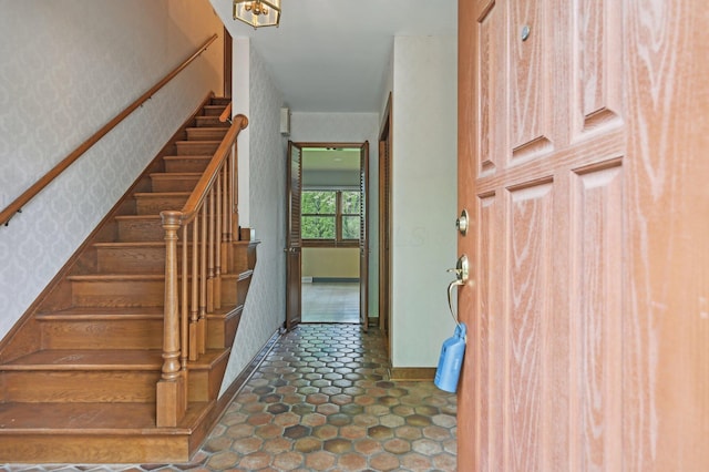 staircase with wallpapered walls and baseboards