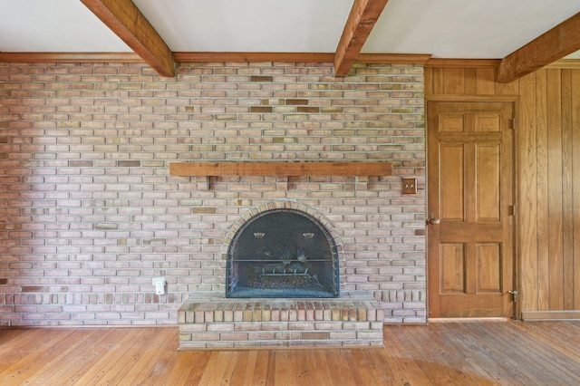 unfurnished living room featuring beamed ceiling, hardwood / wood-style floors, and wood walls