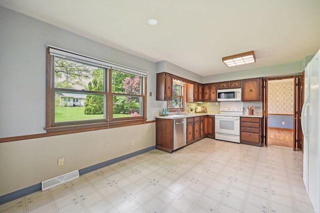 kitchen with white appliances, light floors, a sink, light countertops, and baseboards