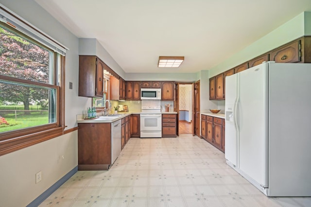 kitchen with white appliances, a sink, light floors, and light countertops