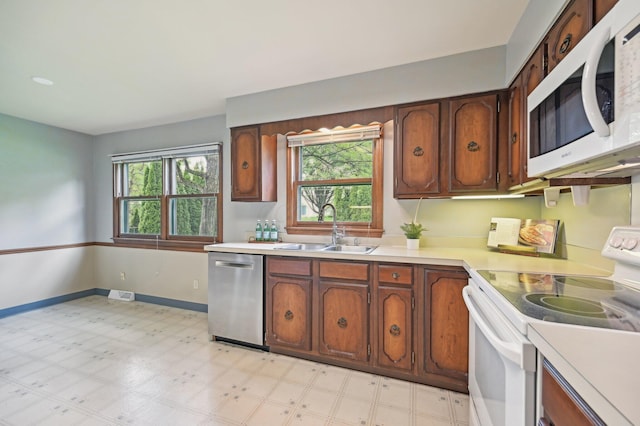 kitchen with white appliances, a sink, light countertops, and light flooring