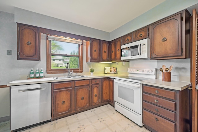kitchen with white appliances, a sink, light floors, and light countertops