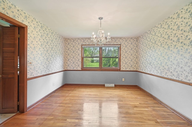 unfurnished dining area with a chandelier, light wood-style flooring, wallpapered walls, and baseboards