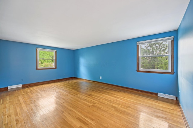 unfurnished room with light wood-type flooring and baseboards