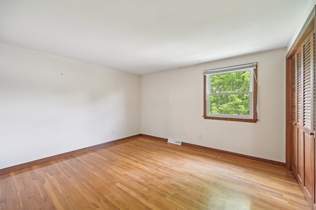 unfurnished bedroom featuring baseboards, light wood-style flooring, and a closet