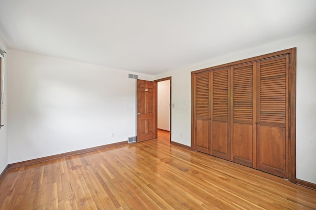 unfurnished bedroom featuring baseboards, a closet, and light wood-type flooring