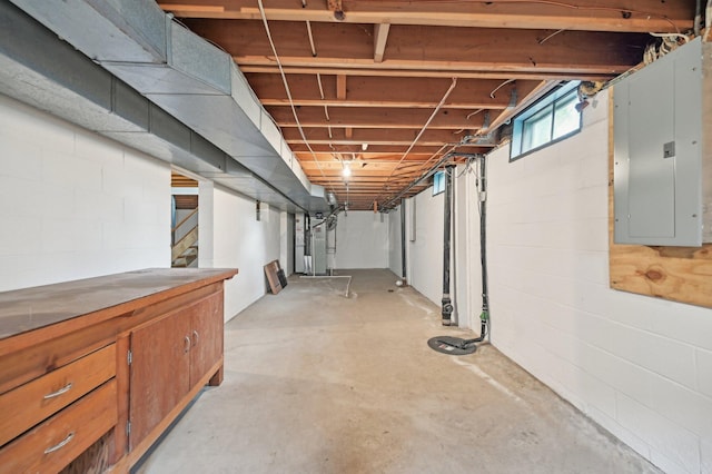 below grade area featuring electric panel, stairway, and heating unit