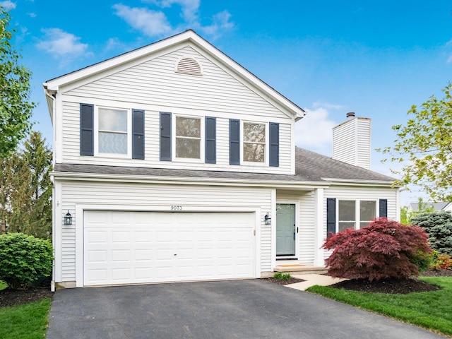 traditional-style home with roof with shingles, a chimney, a garage, and aphalt driveway