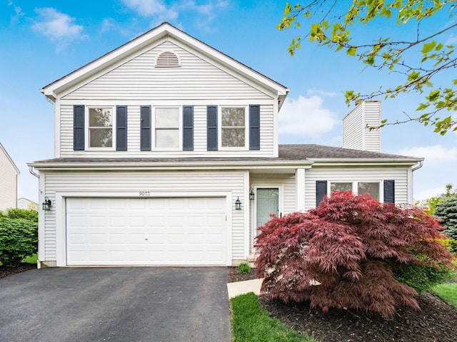 view of front of property featuring an attached garage, a chimney, and driveway