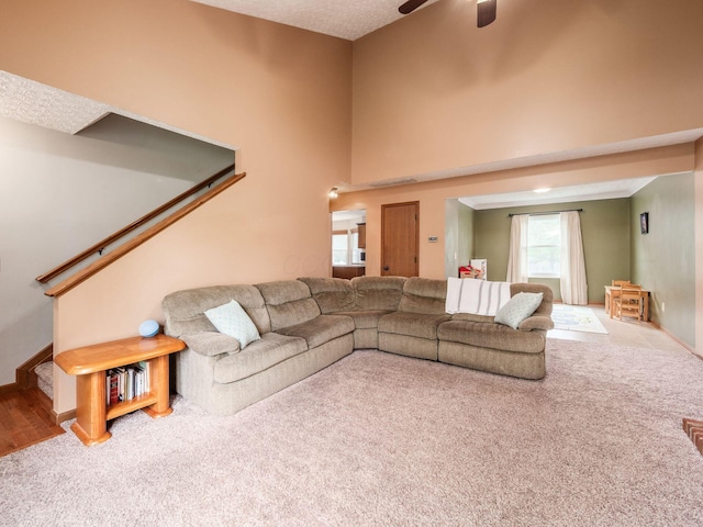 living area featuring carpet, stairway, baseboards, and a ceiling fan