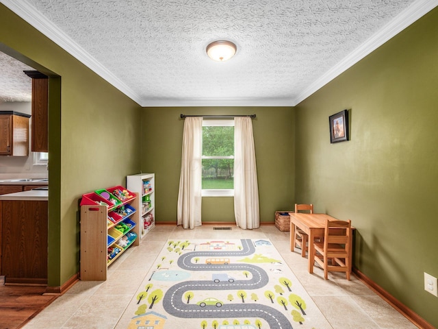 rec room featuring baseboards, ornamental molding, visible vents, and a textured ceiling
