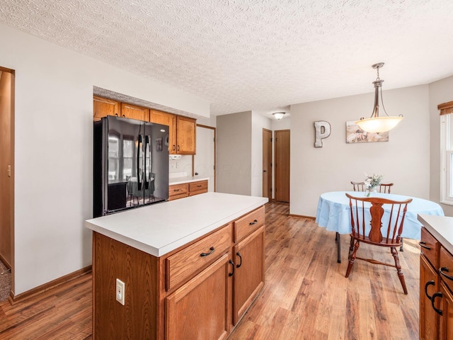 kitchen with light wood-style floors, freestanding refrigerator, light countertops, and brown cabinets