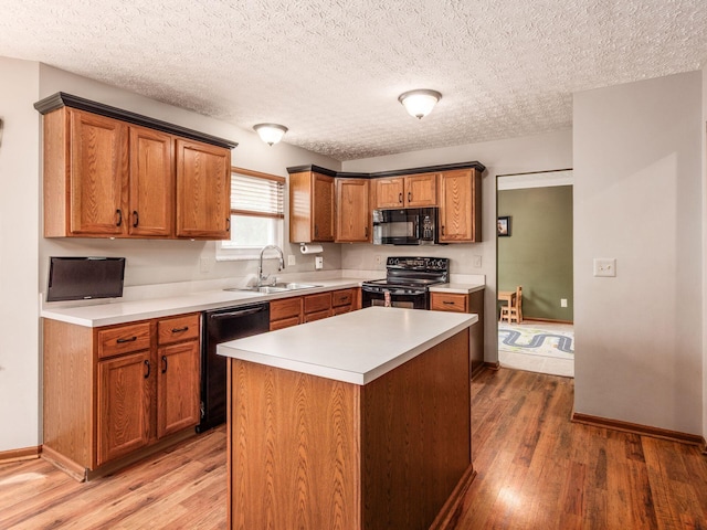kitchen with black appliances, light countertops, light wood-style flooring, and a sink