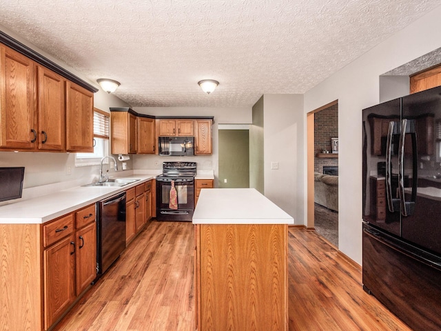 kitchen featuring black appliances, light wood-style floors, light countertops, and a sink