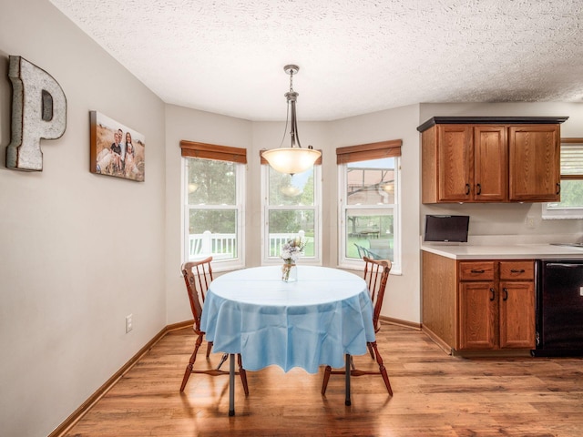 dining space with light wood-style flooring, a textured ceiling, and baseboards