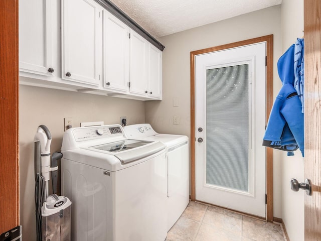laundry room with cabinet space, a textured ceiling, separate washer and dryer, and light tile patterned floors