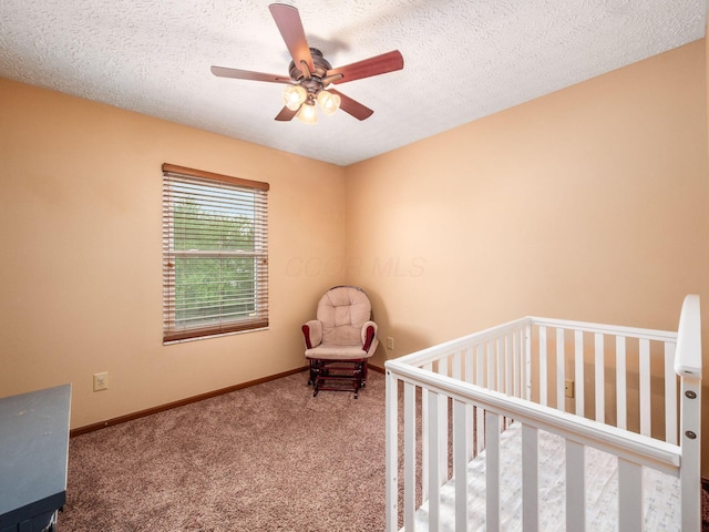 unfurnished bedroom featuring baseboards, a textured ceiling, a nursery area, and carpet