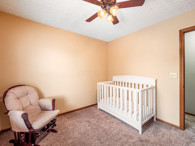 carpeted bedroom featuring a crib, baseboards, and a ceiling fan