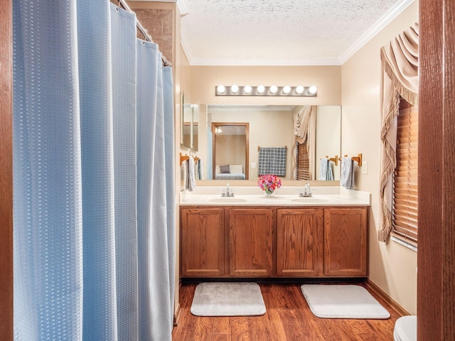 full bathroom with double vanity, wood finished floors, ornamental molding, and a sink