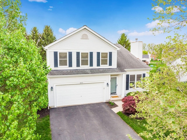 traditional-style home with a chimney, driveway, roof with shingles, and a garage