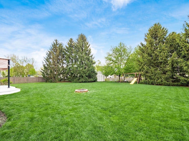 view of yard featuring a playground, an outbuilding, a fenced backyard, and a storage unit