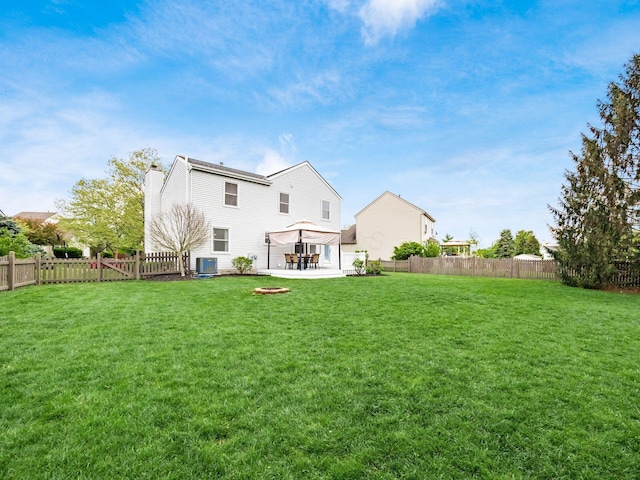 rear view of house featuring a chimney, a gazebo, a fenced backyard, a yard, and a patio area