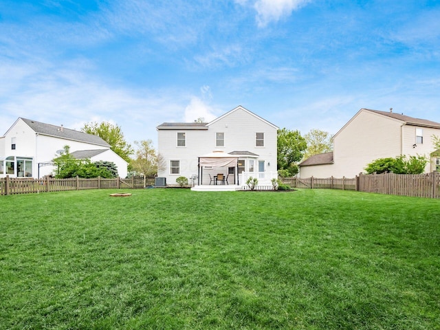 rear view of house featuring a yard, a patio area, and a fenced backyard
