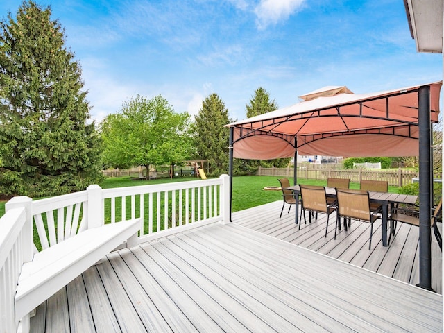 wooden terrace featuring a lawn, a gazebo, outdoor dining area, and a fenced backyard
