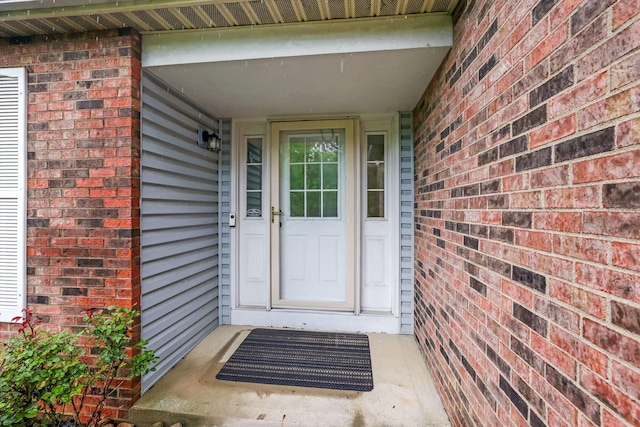 view of exterior entry featuring brick siding