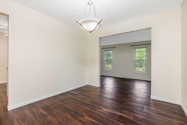 empty room featuring dark wood-style flooring and baseboards