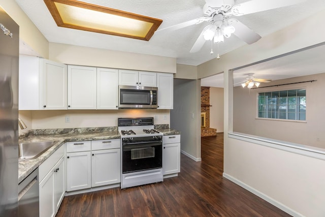kitchen with appliances with stainless steel finishes, ceiling fan, white cabinetry, dark wood finished floors, and baseboards