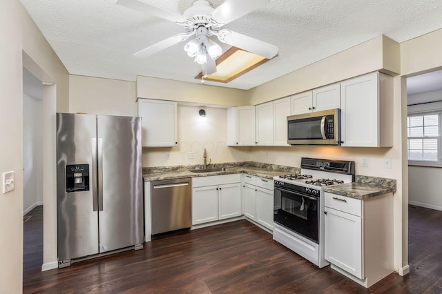 kitchen with stainless steel appliances, a sink, ceiling fan, white cabinetry, and dark wood-style floors