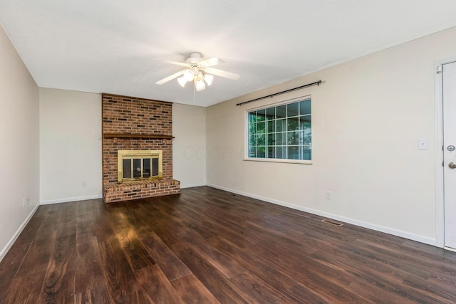 unfurnished living room featuring ceiling fan, wood finished floors, a brick fireplace, and baseboards