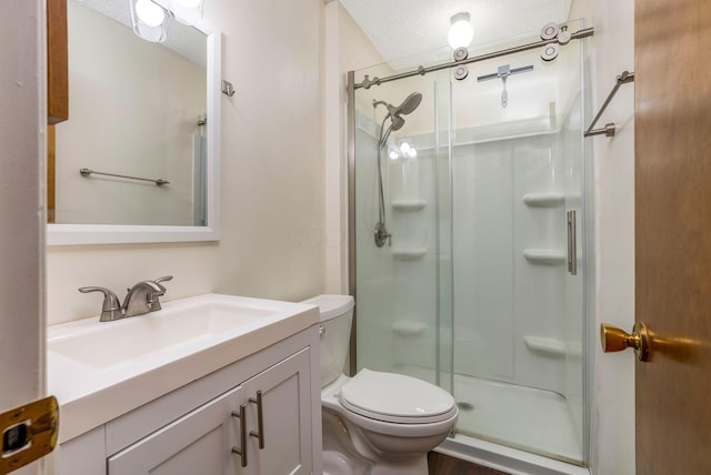 full bathroom featuring a textured ceiling, a stall shower, toilet, and vanity