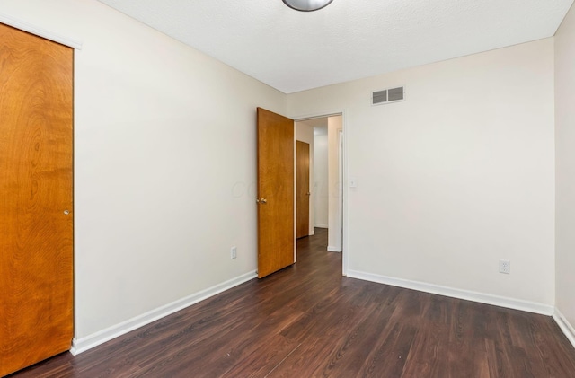 unfurnished room with baseboards and dark wood-style flooring