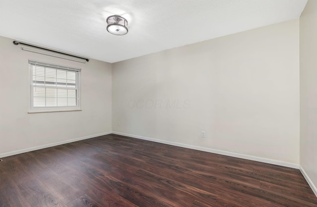 spare room with baseboards and wood finished floors