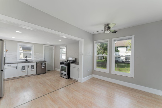 901 Campbell Ave, Columbus, OH 43223 - kitchen featuring appliances with stainless steel finishes, a sink, light wood finished floors, backsplash, and a ceiling fan