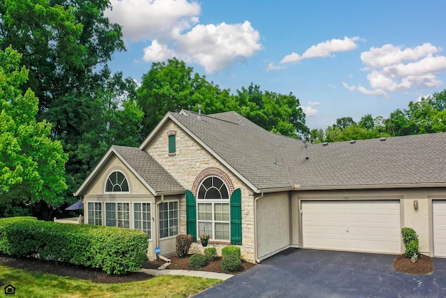 7742 Blue Juniper Dr, Westerville, OH 43082 - view of front facade featuring stone siding, stucco siding, asphalt driveway, a garage, and a shingled roof