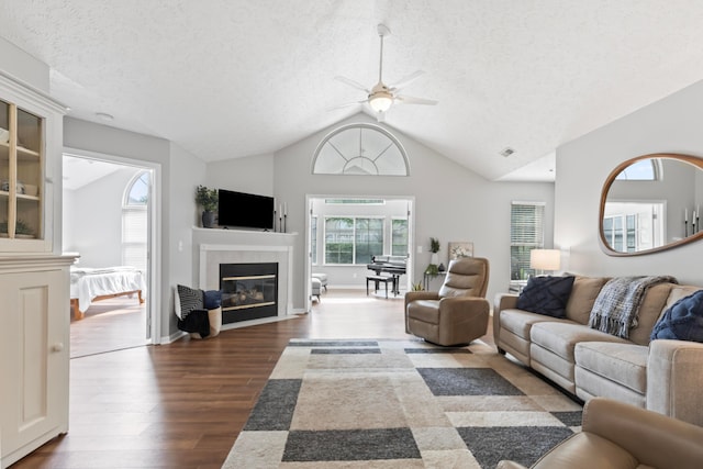 7742 Blue Juniper Dr, Westerville, OH 43082 - living area featuring ceiling fan, dark wood-style flooring, vaulted ceiling, a textured ceiling, and a tiled fireplace