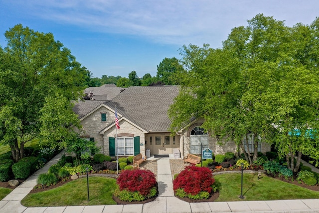 7742 Blue Juniper Dr, Westerville, OH 43082 - view of front of property featuring stone siding, roof with shingles, and a front lawn