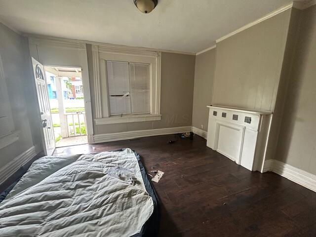 unfurnished bedroom featuring baseboards, dark wood-style flooring, crown molding, and access to exterior