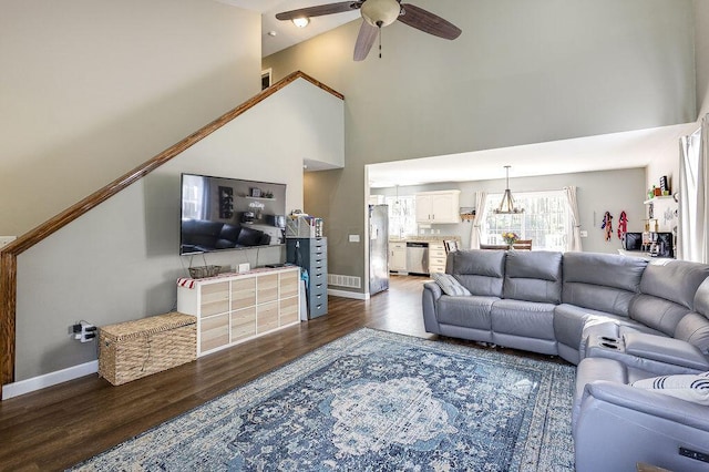 living room with a ceiling fan, baseboards, dark wood finished floors, visible vents, and high vaulted ceiling