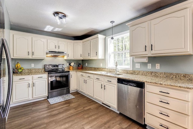 kitchen with a sink, stainless steel appliances, a textured ceiling, dark wood finished floors, and under cabinet range hood
