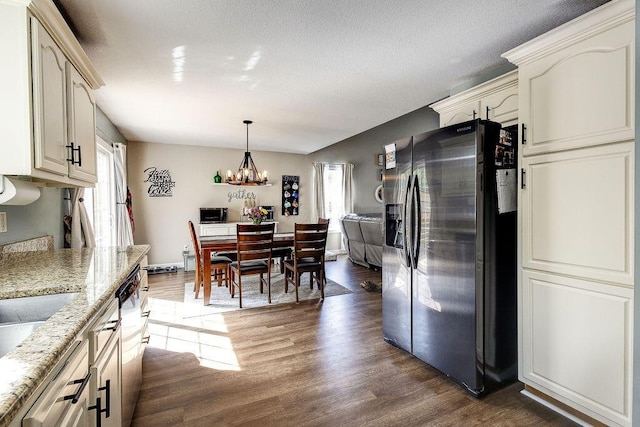 kitchen with stainless steel appliances, decorative light fixtures, light stone counters, dark wood-type flooring, and a notable chandelier