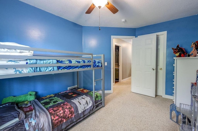 bedroom featuring light colored carpet, a textured ceiling, baseboards, and ceiling fan